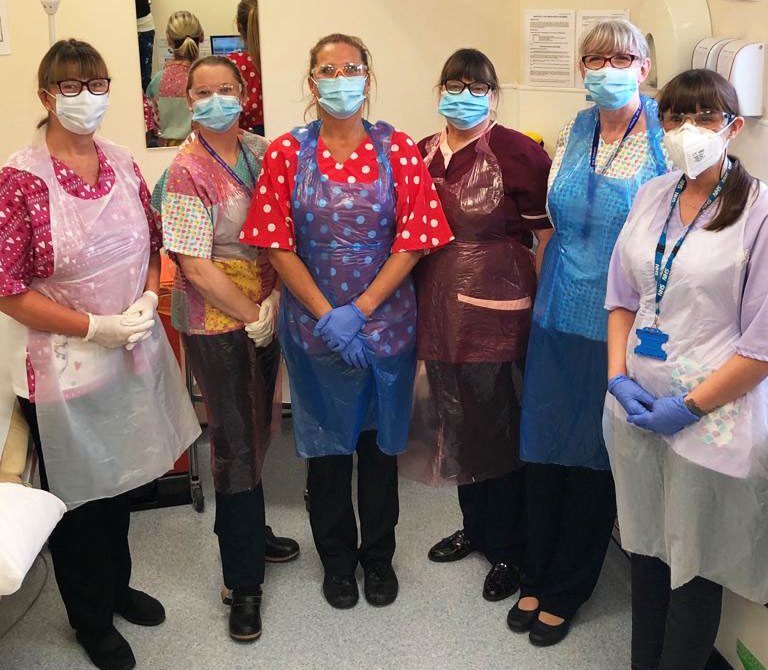 Nurses wearing personal protective equipment, or PPE, including masks, gloves and plastic aprons.